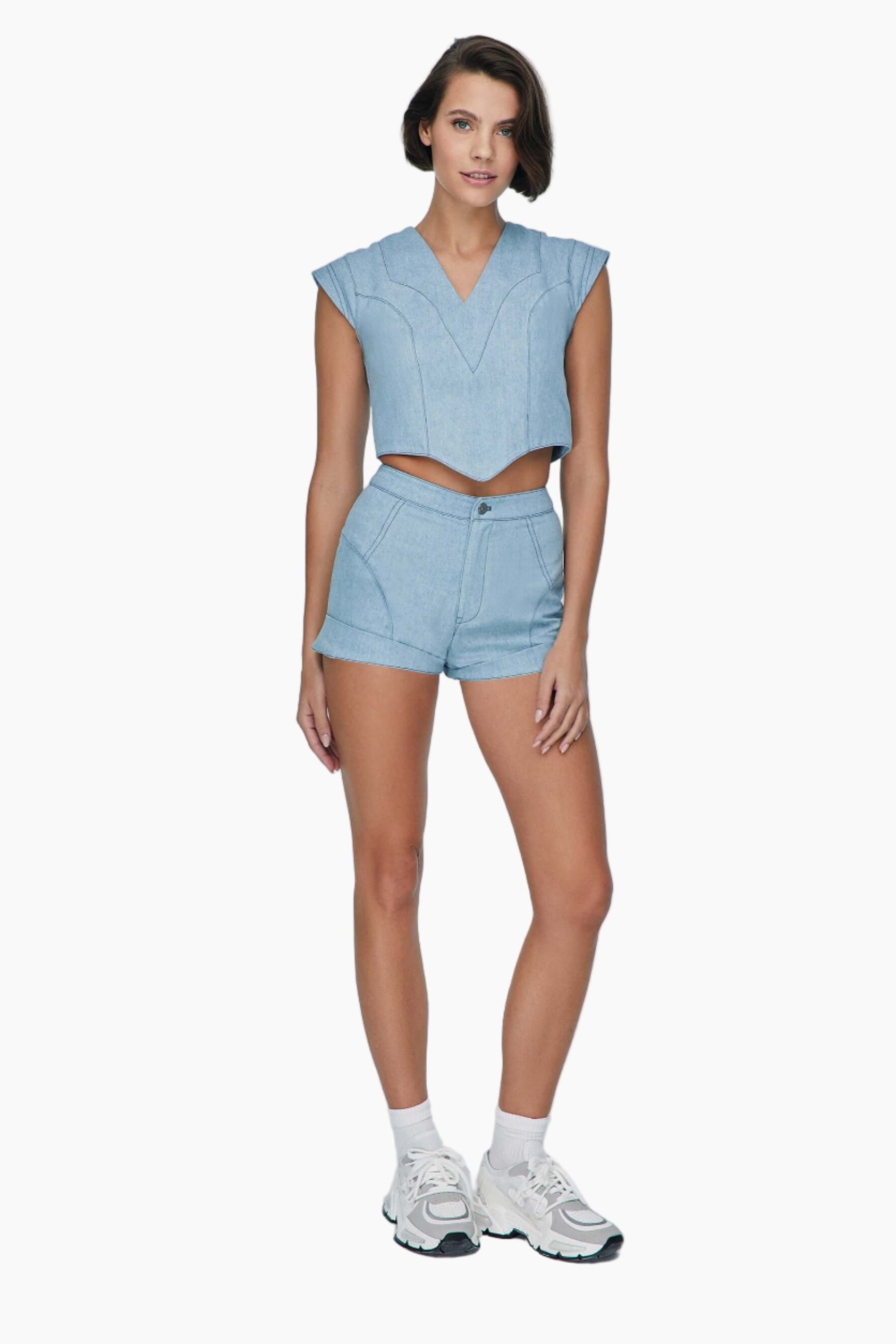 Woman wearing a light blue sleeveless top and shorts set. denim short Feature mid-rise belt. It is secured with a metallic button and a zipper fastening.