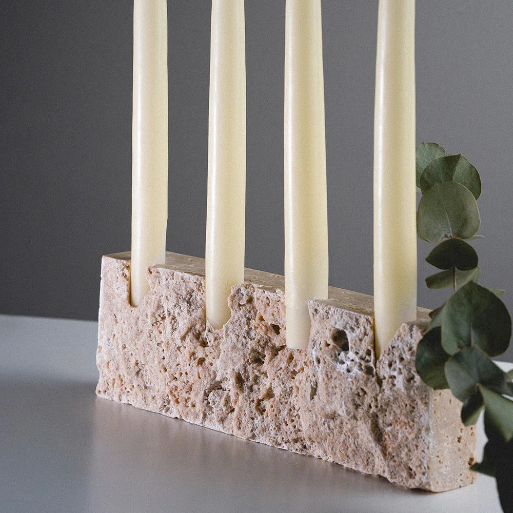 Candle holder with four white candles on a gray background