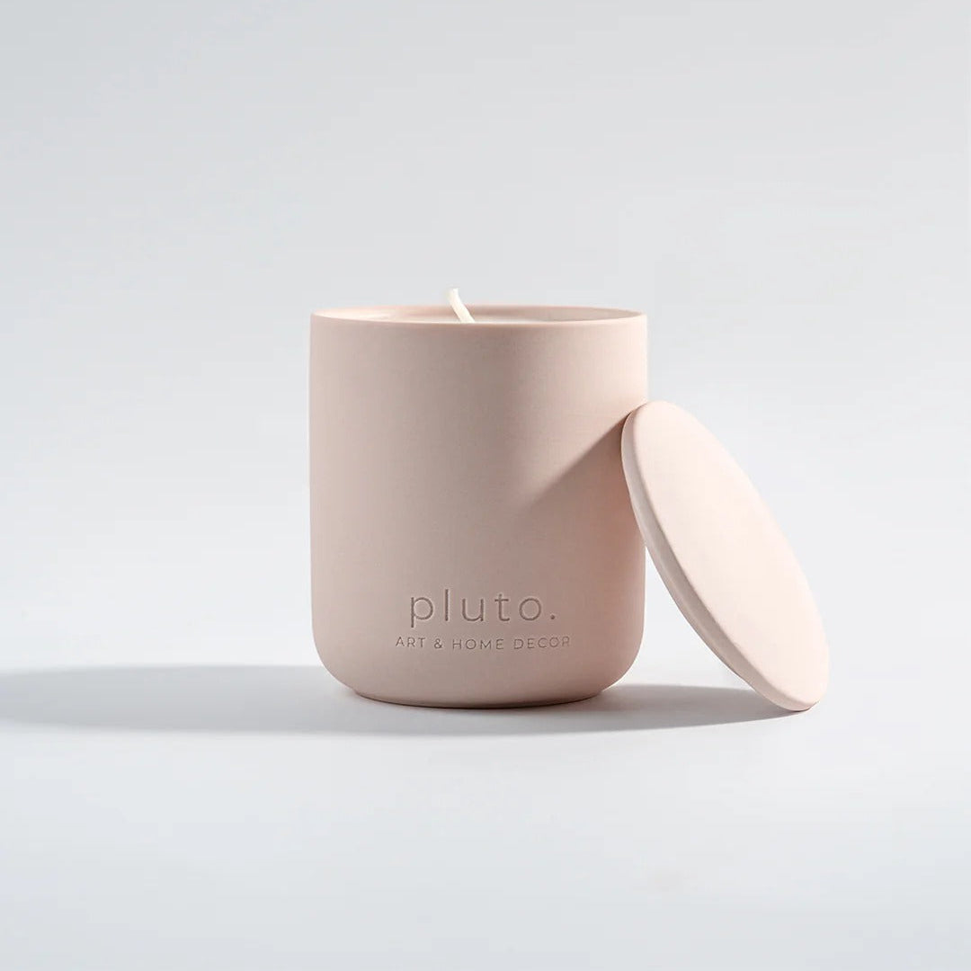 Pink candle with lid on a light gray background, featuring the brand 'pluto'.