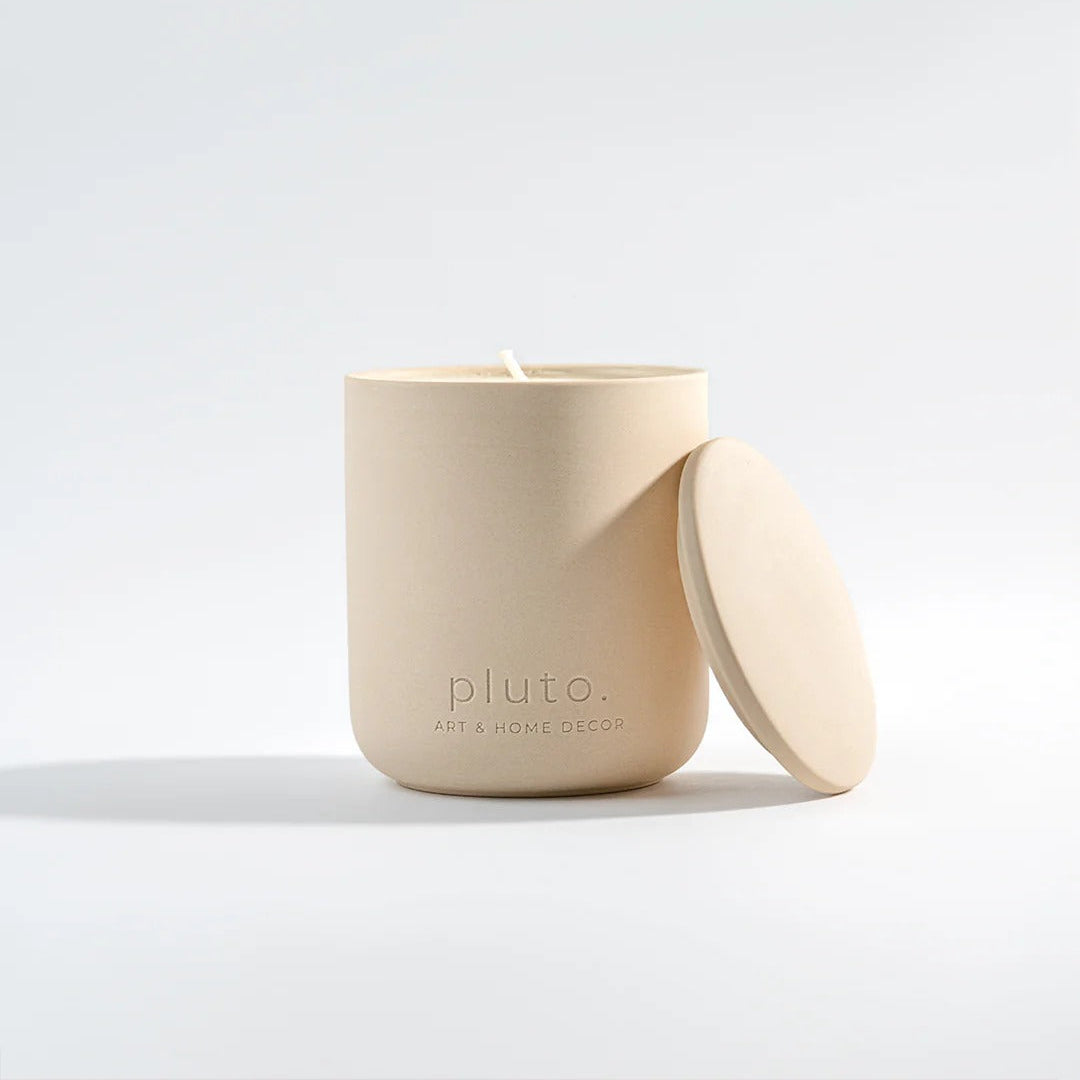 Beige candle with lid on a white background, featuring the brand 'pluto'.
