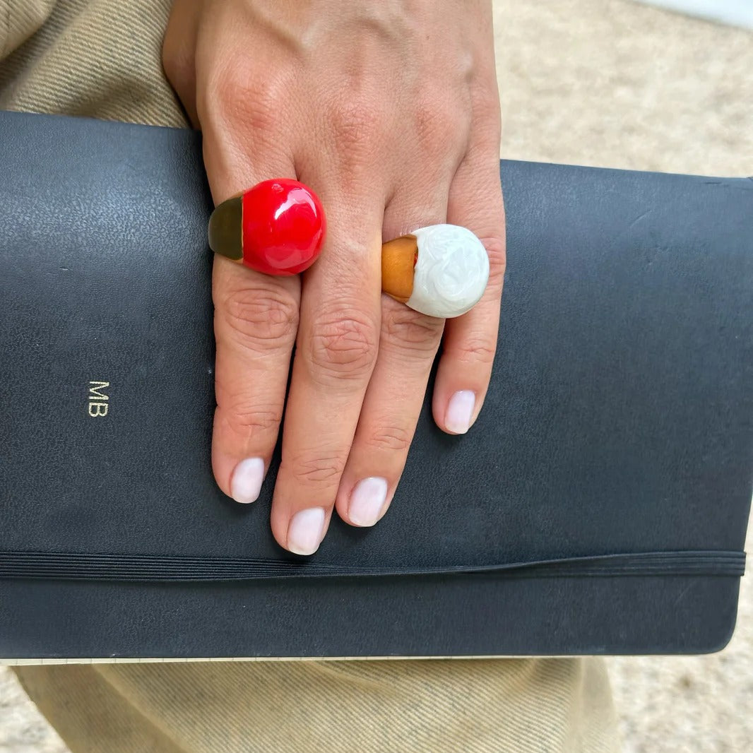 Hand holding a black clutch with colorful rings on a blurred background