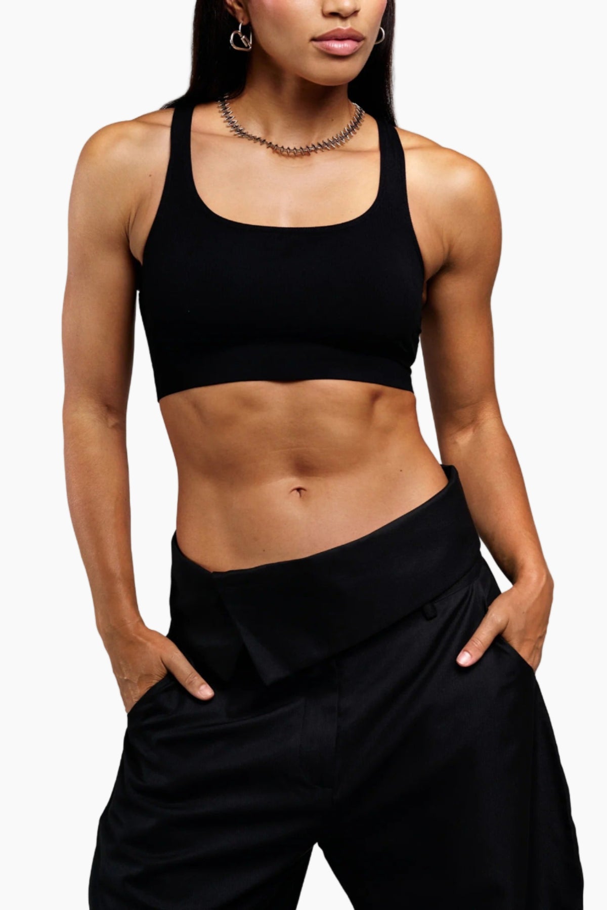 Person wearing a black sports bra and black pants on a white background