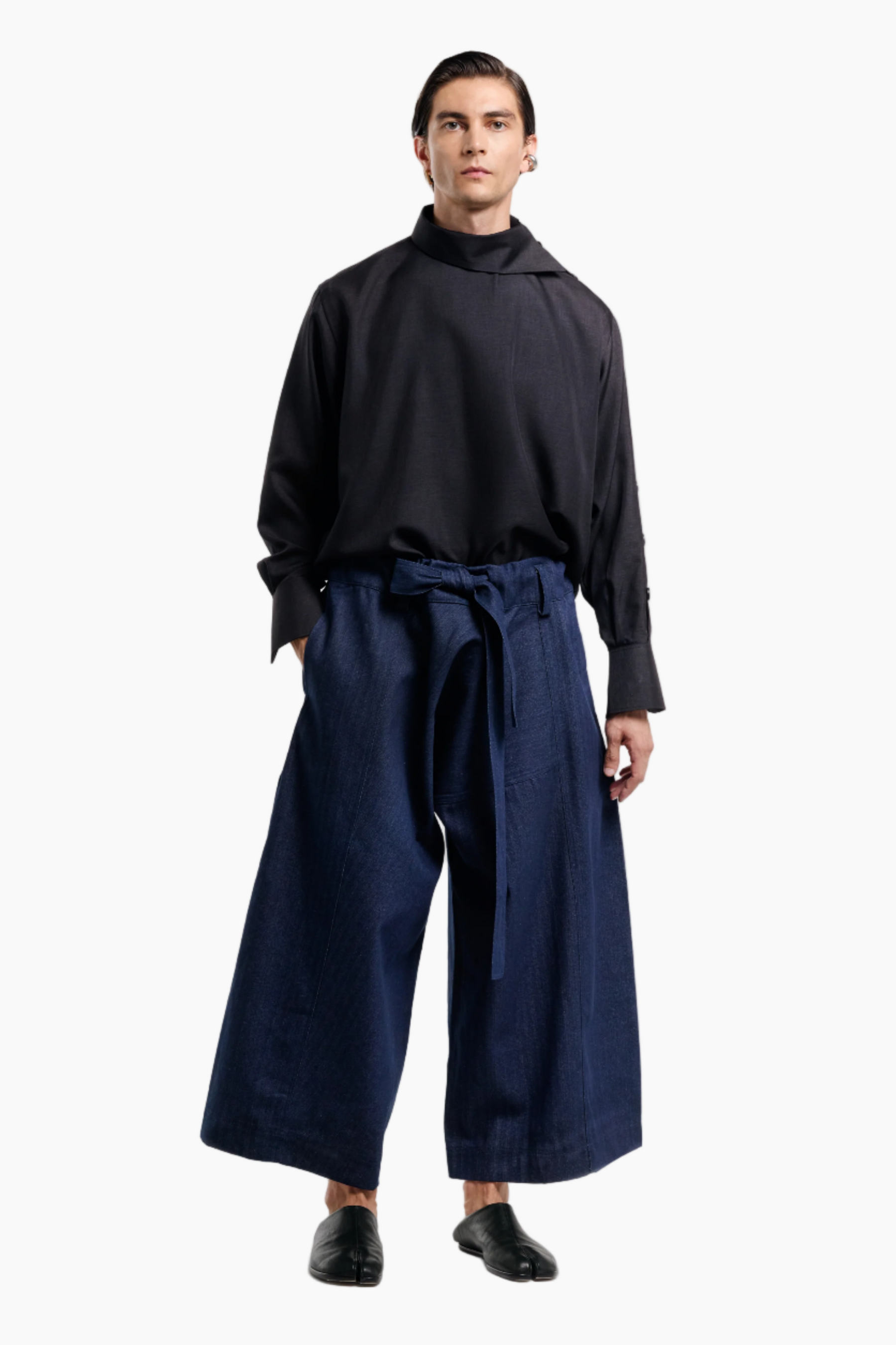 Person wearing a black long-sleeve top and navy wide-leg pants on a white background