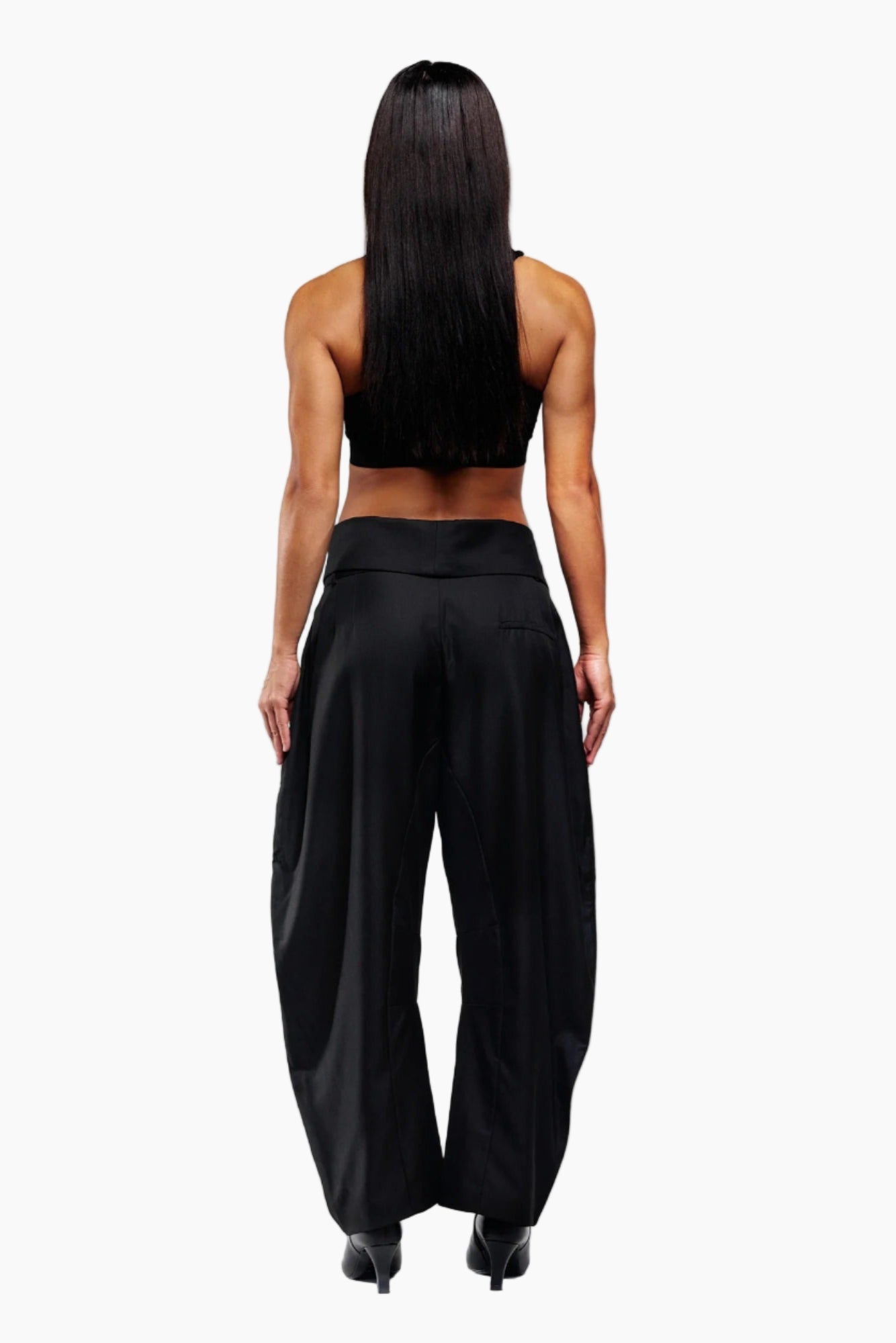Person wearing a black sleeveless top and wide-leg pants on a white background