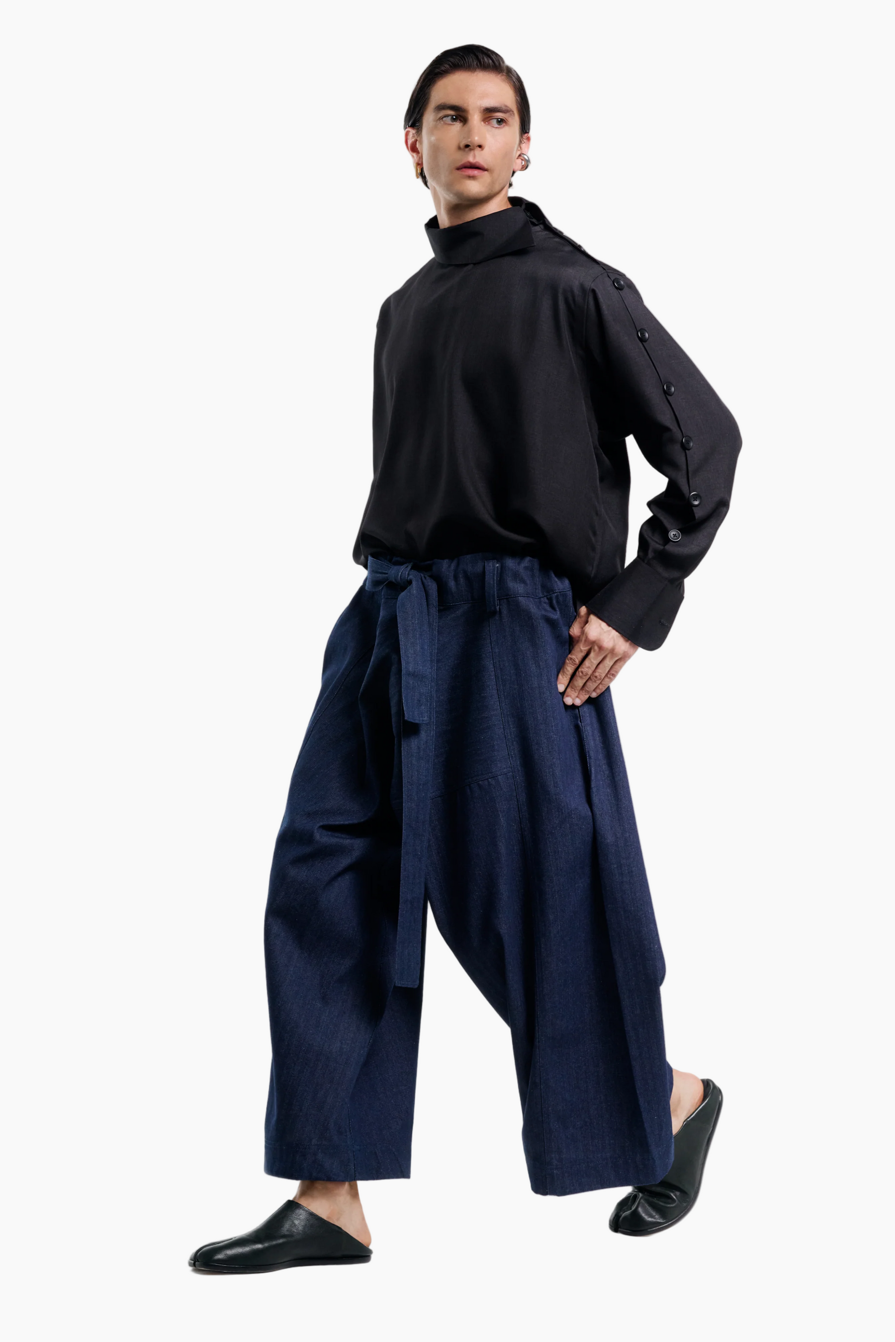 Person wearing a black top and navy pants on a white background