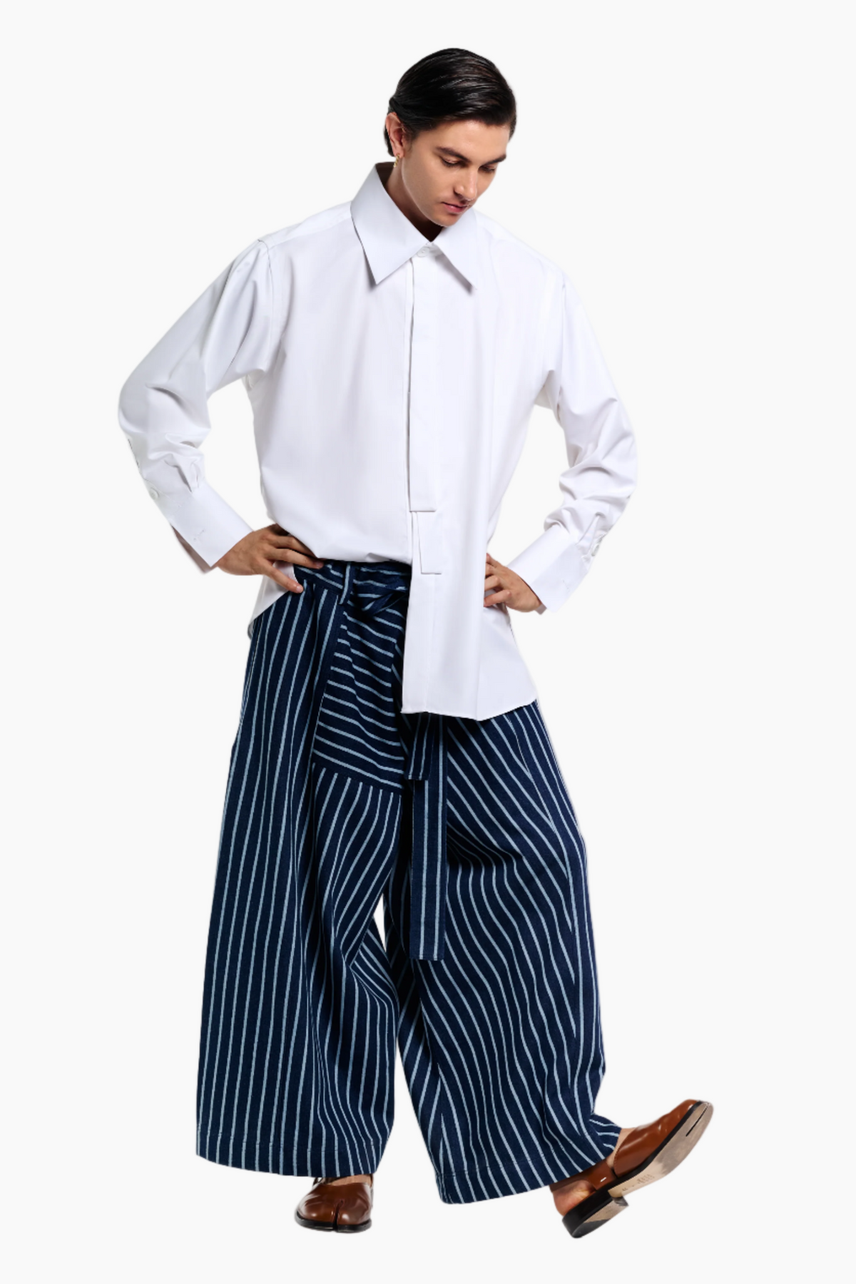 Person wearing a white shirt and blue striped pants on a light gray background