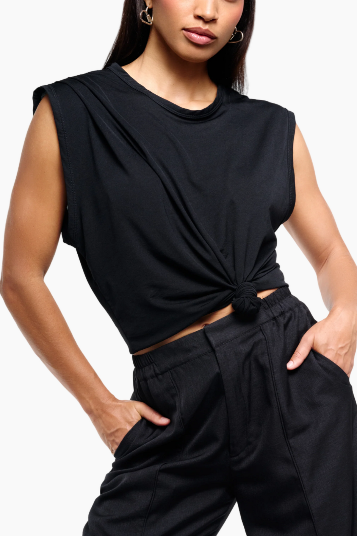 Person wearing a black sleeveless top and wide-leg pants on a white background