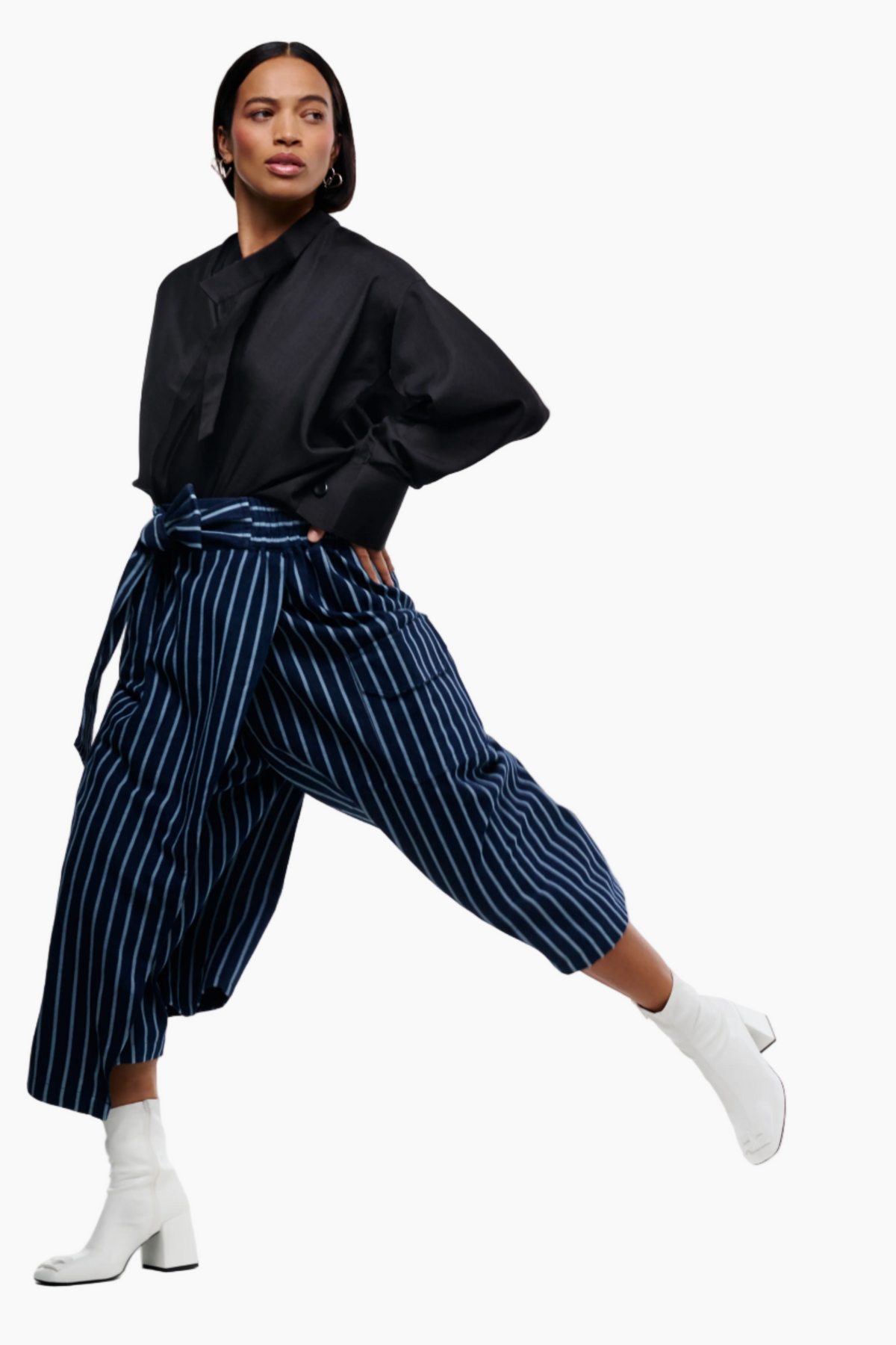 Woman wearing a black top and blue striped pants on a white background