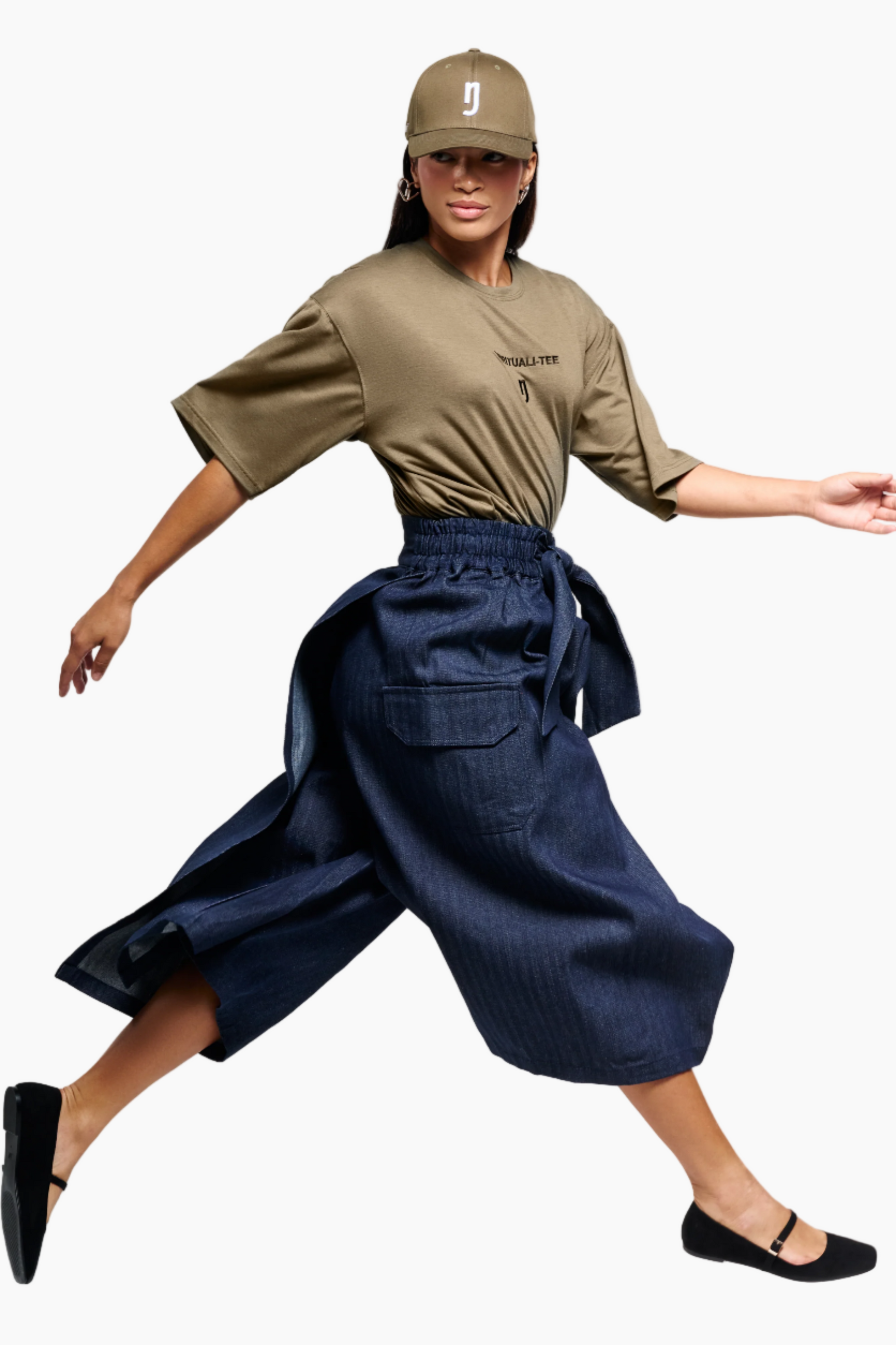 Woman wearing a beige shirt, navy pants, and a cap on a white background