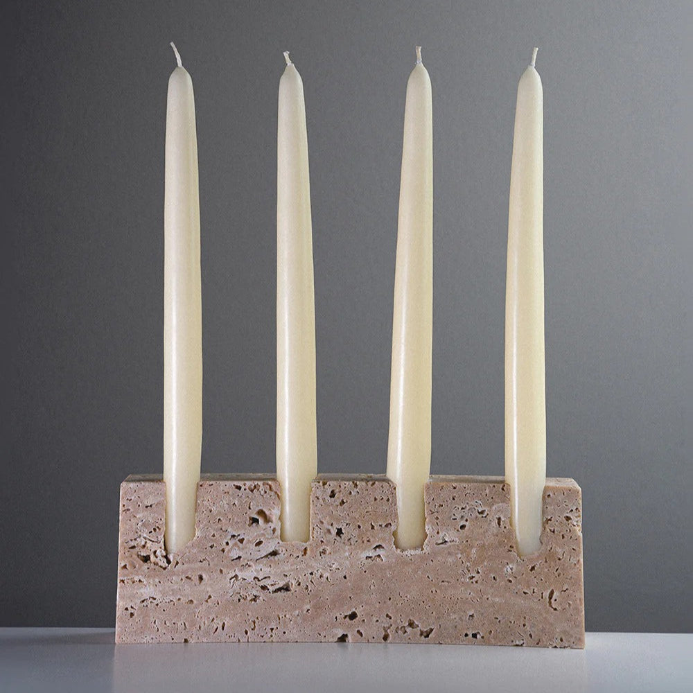 Candle holder with four white candles on a gray background