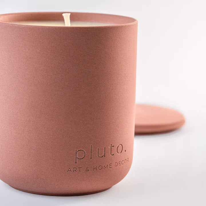 Terracotta-colored candle with 'pluto. Art & Home Decor' branding