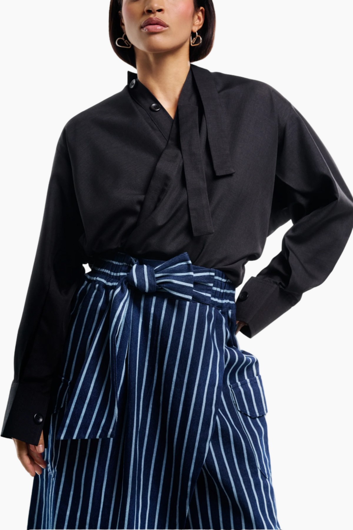 Person wearing a black blouse and blue striped pants on a white background
