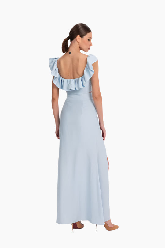 linen set featuring a charming top and skirt ensemble. The top boasts delicate ruffles adorning the neckline. The skirt features a flattering high waist design with a slit in the front.