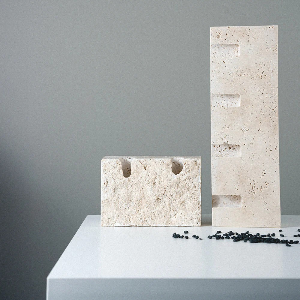 Two stone sculptures on a white surface with a gray background