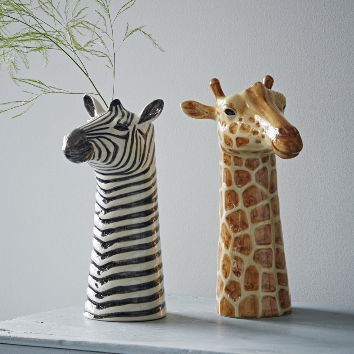 Ceramic zebra and giraffe head vases on a light surface
