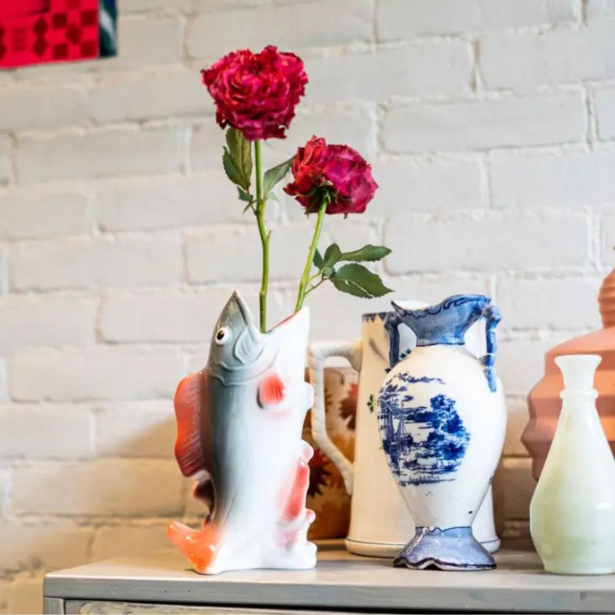 Vase shaped like a fish with red flowers
