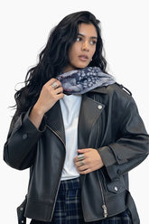 Woman wearing a black leather jacket with a white shirt and plaid skirt