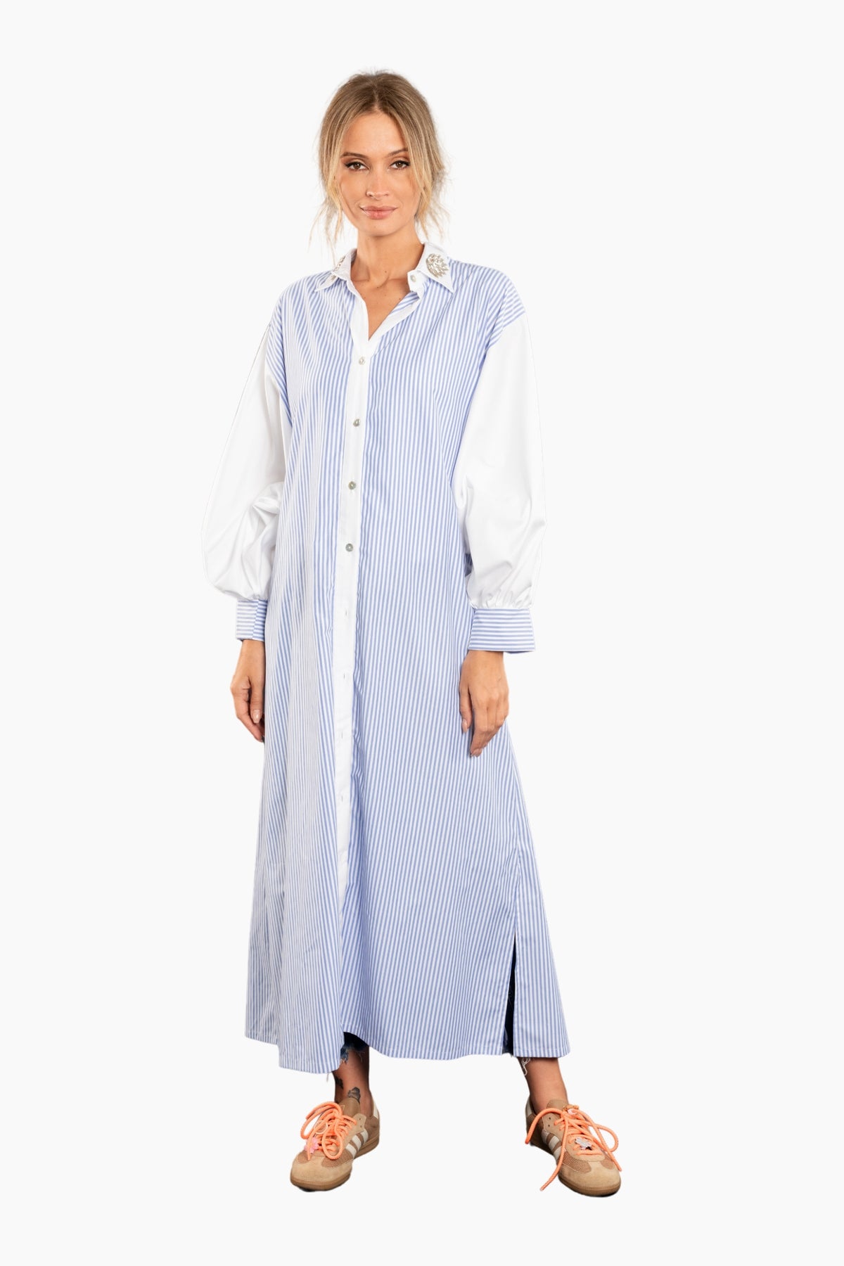 Woman wearing a long blue and white striped shirt dress on a white background
