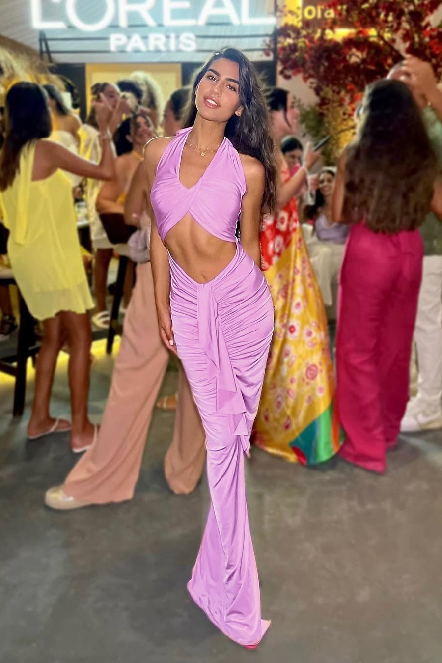 Woman in a pink dress at a social event with 'L'Oreal Paris' branding in the background.
