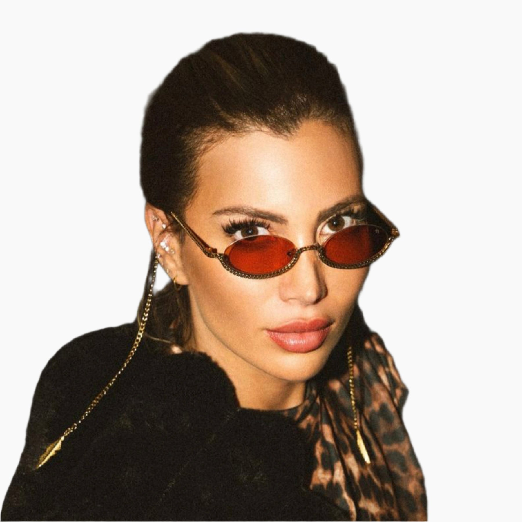 Woman wearing a black outfit with a leopard print scarf against a dark background and a Sunglasses with orange lenses and gold chain