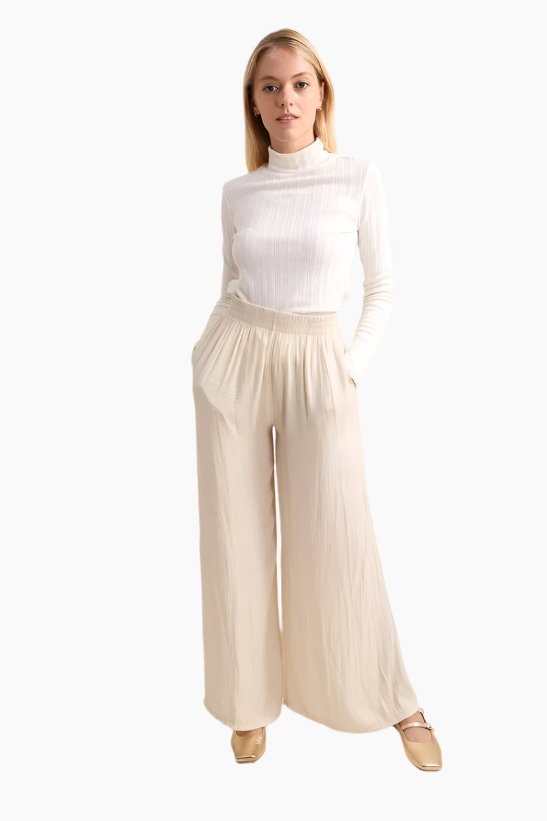 Woman wearing a white turtleneck and beige wide-leg pants