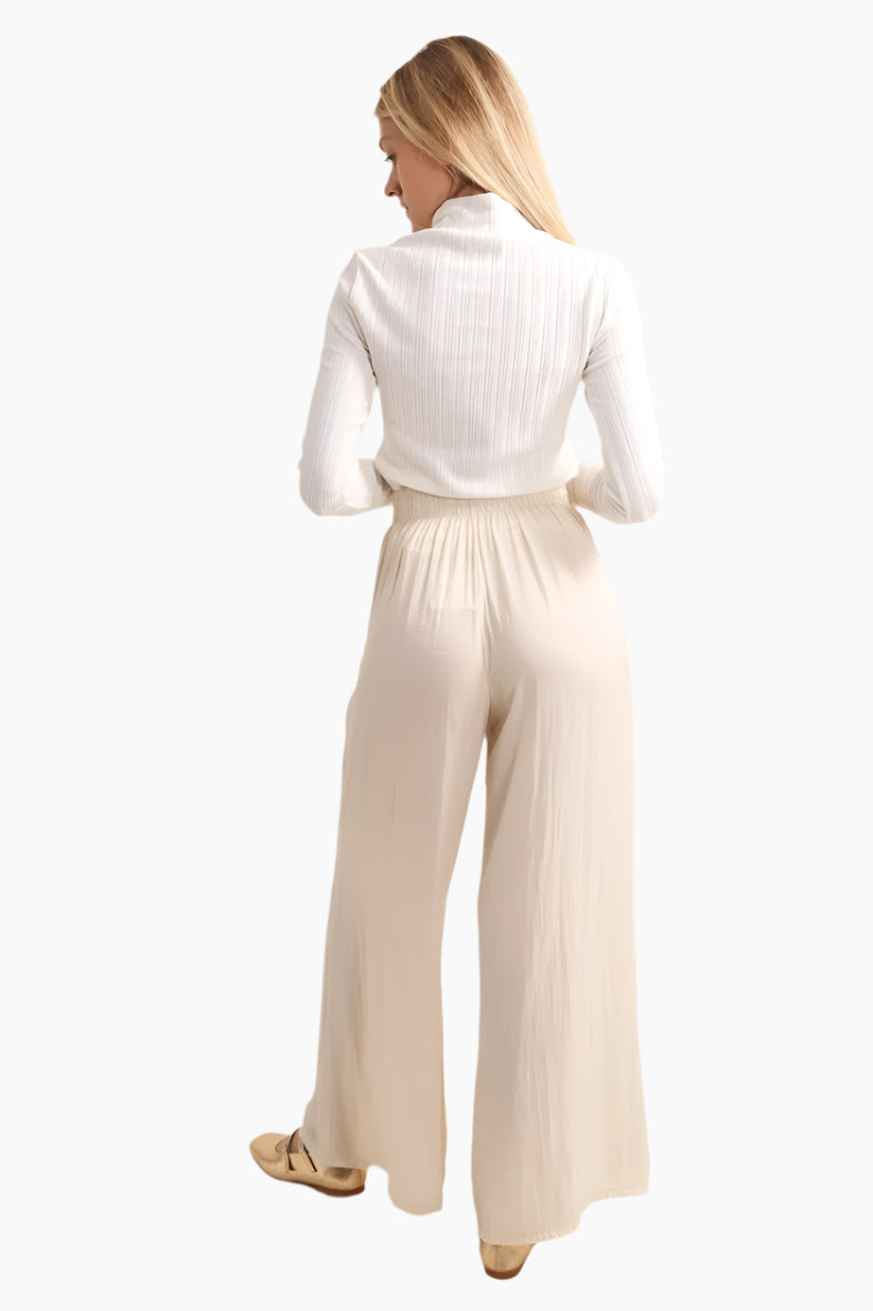 Woman wearing a white ribbed sweater and beige wide-leg pants