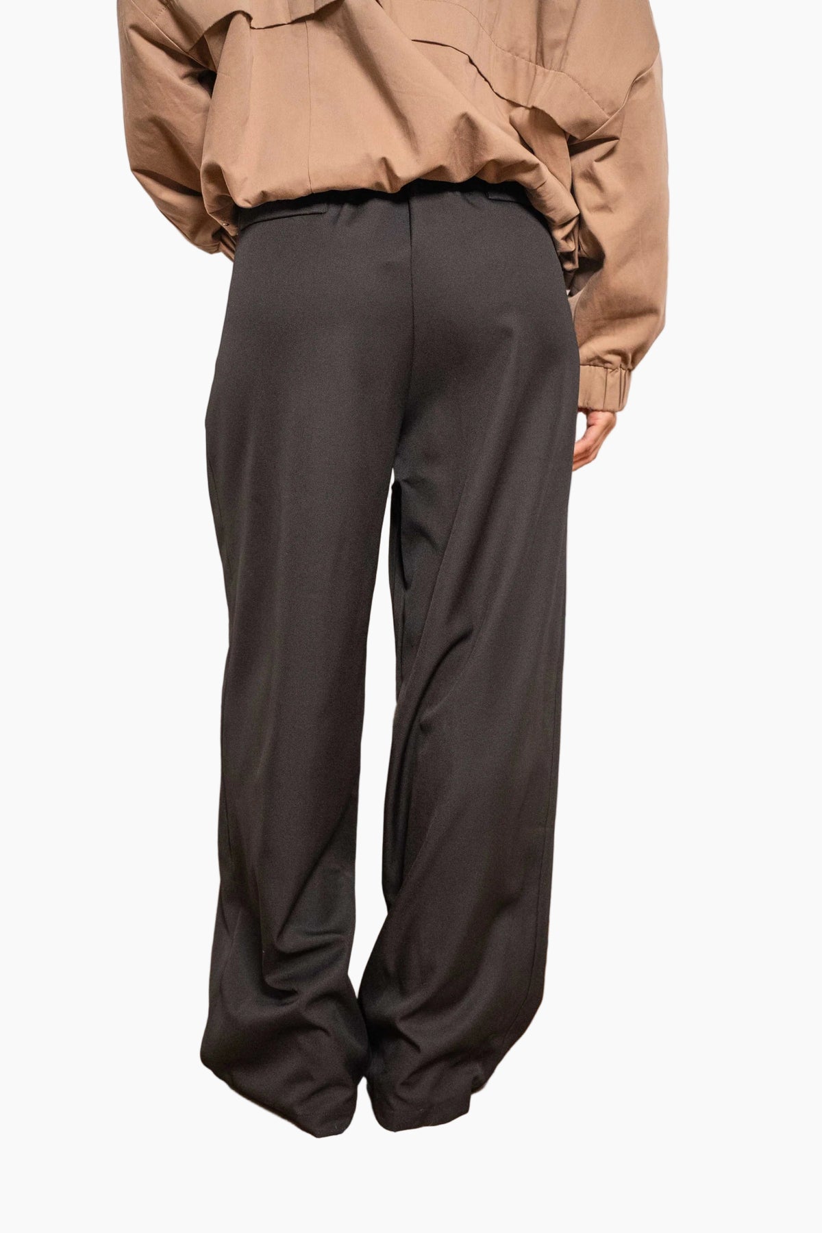 Person wearing a beige jacket and brown pants