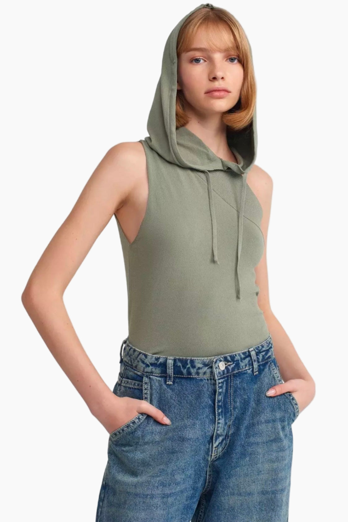 Person wearing a green sleeveless hoodie and blue jeans on a white background