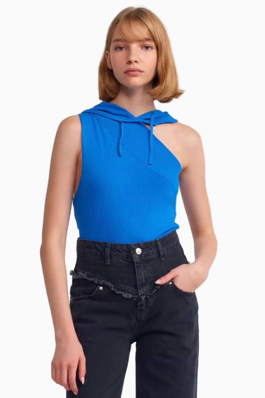 Woman wearing a blue sleeveless top with a hood and black pants on a white background