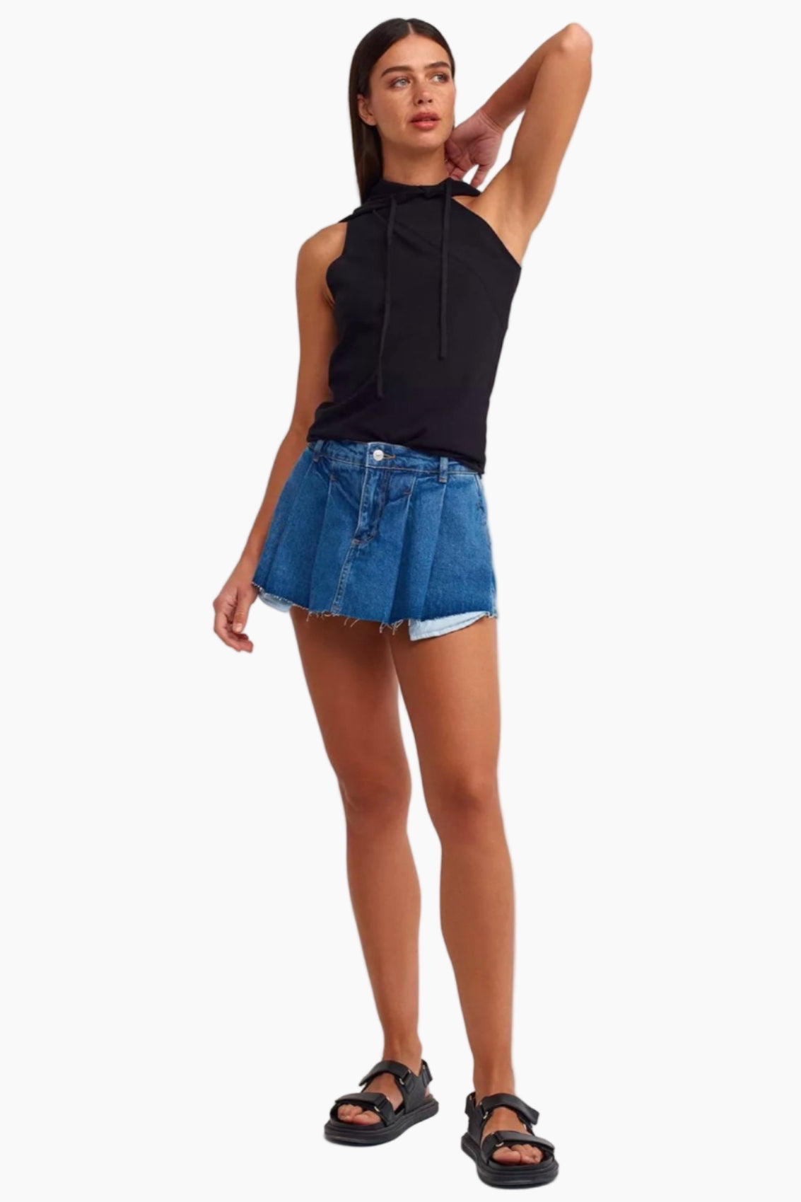 Woman wearing a black sleeveless top and denim skirt on a white background