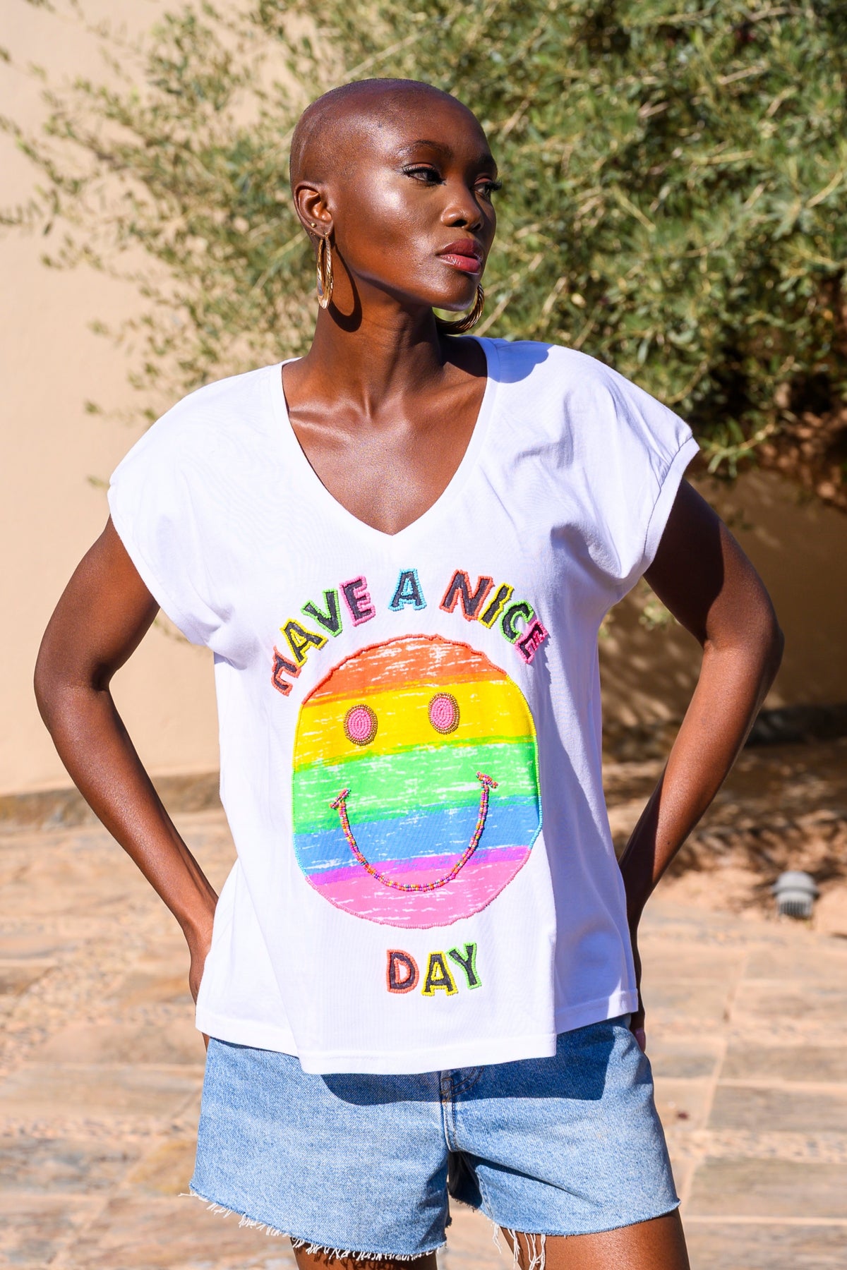 Woman wearing a white t-shirt with a colorful smiley face design and text.