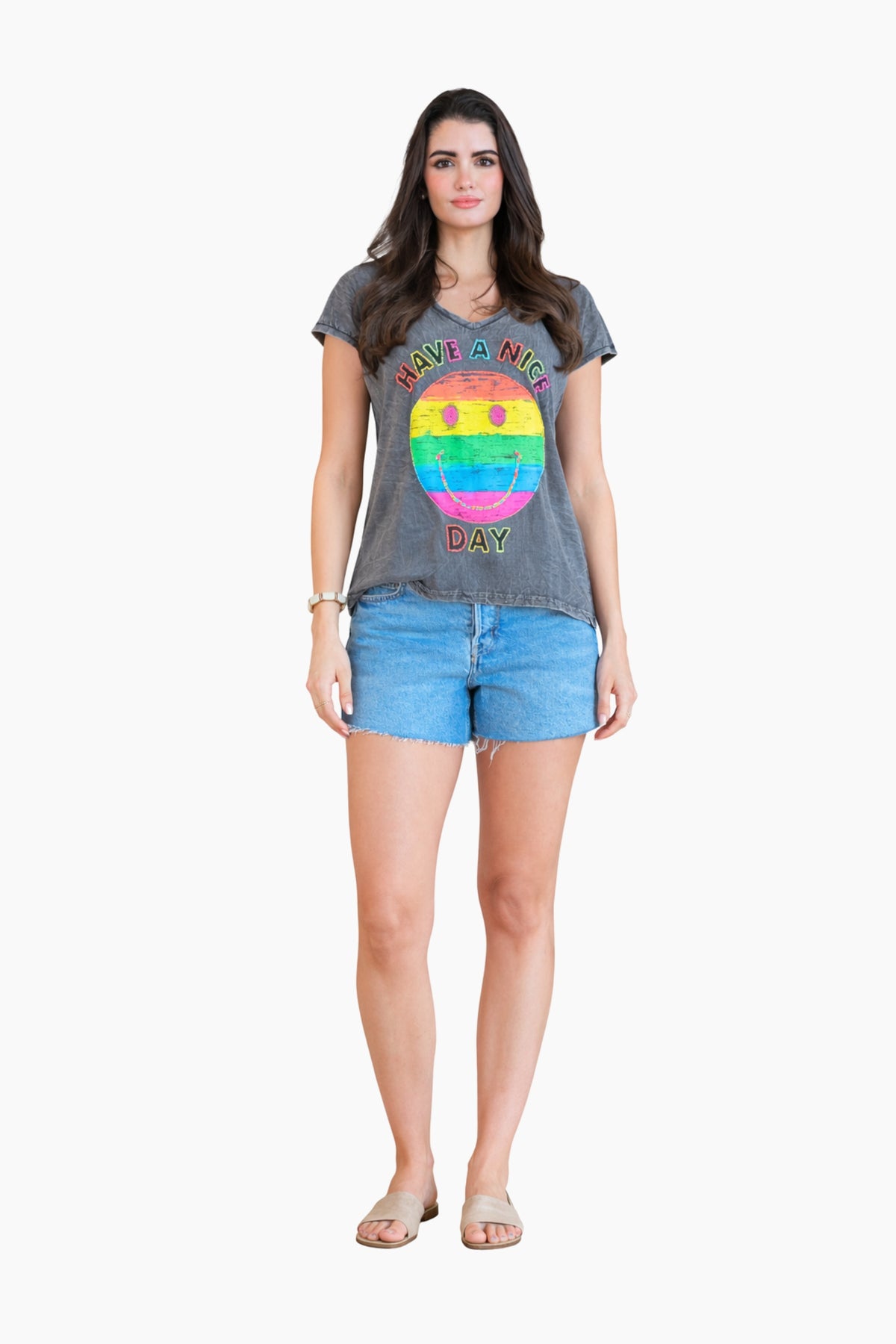 Woman wearing a gray t-shirt with a colorful graphic and denim shorts on a white background