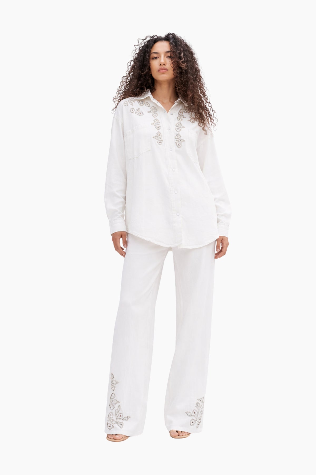 Woman wearing a white pajama set with lace details on a white background