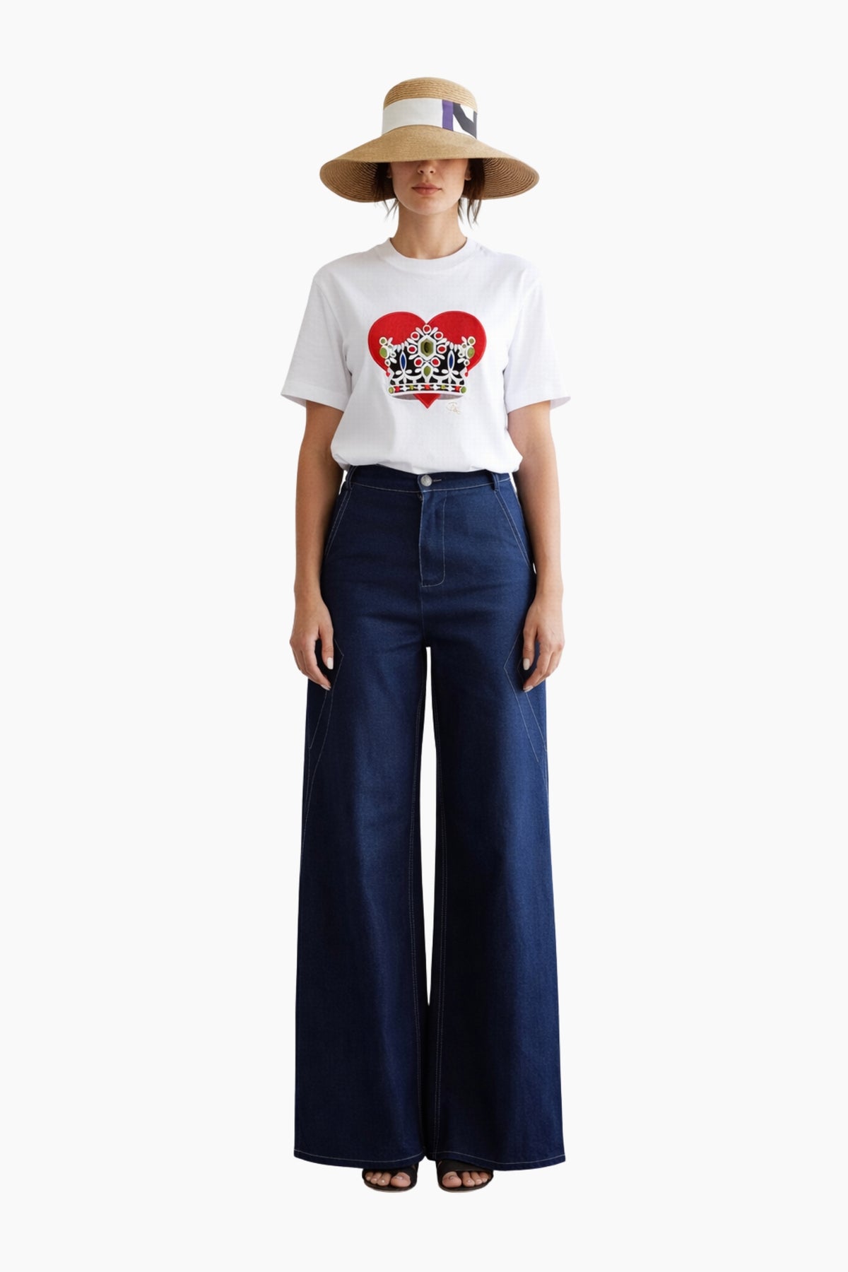 Person wearing a white t-shirt with a graphic design, blue jeans, and a straw hat on a white background