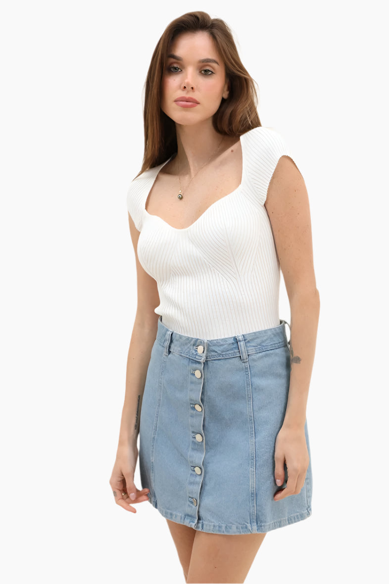 Woman wearing a white sleeveless top and denim skirt