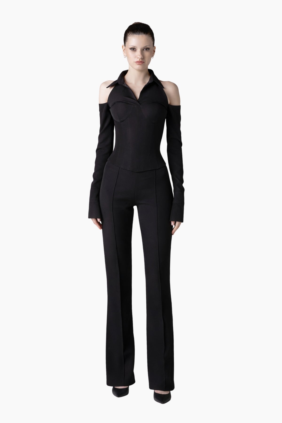 Woman wearing a black outfit with long sleeves and high-waisted pants on a white background