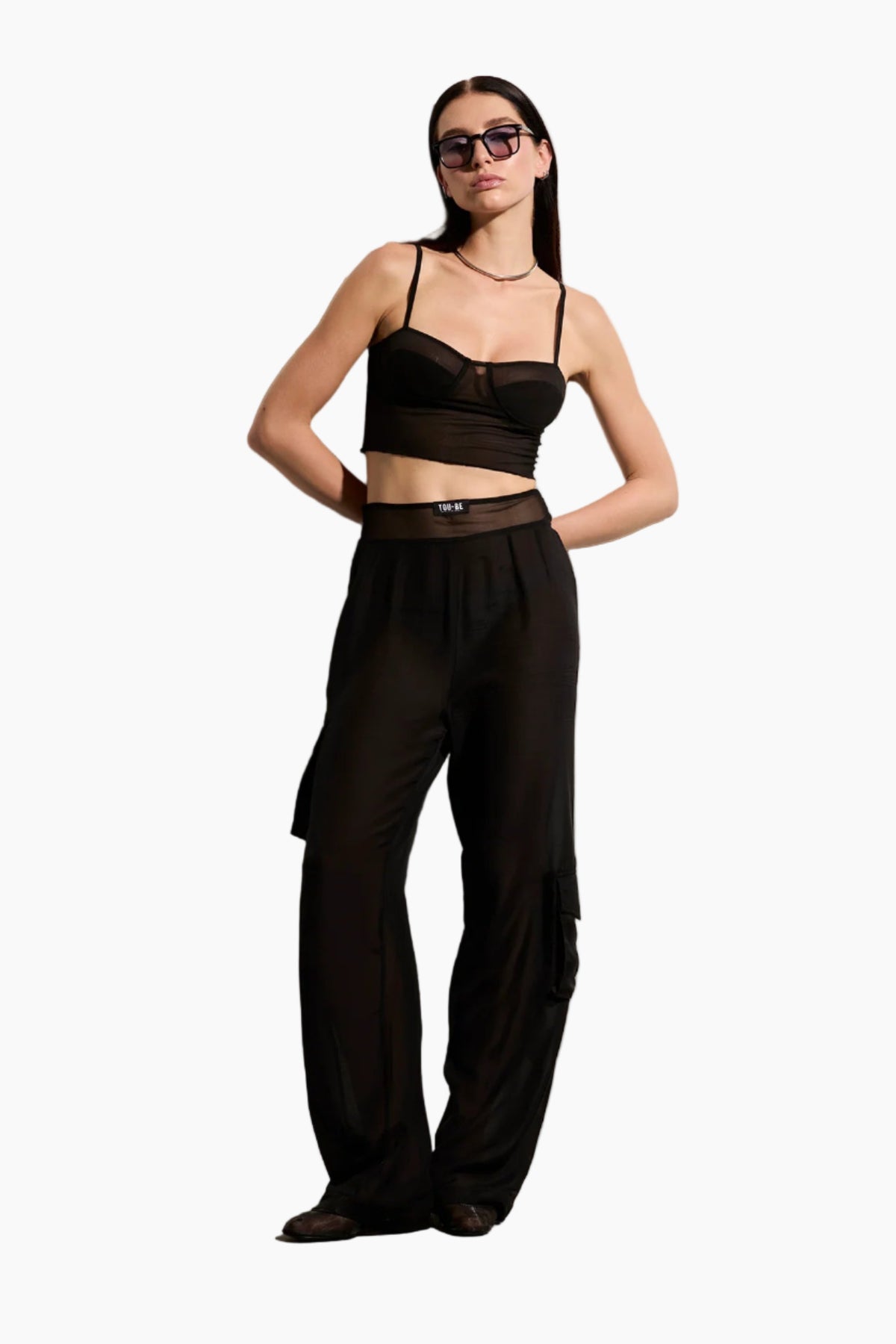 Woman wearing a black outfit with Voile pants with asymmetrical side pockets and a mesh waist detail