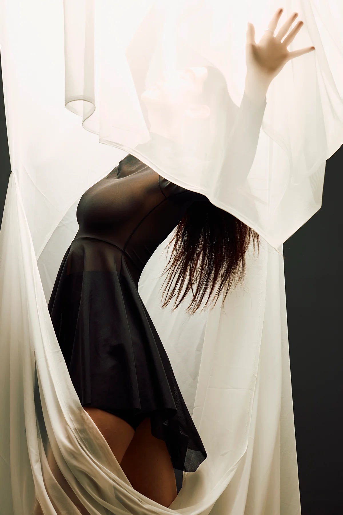 Person wearing a black dress with sheer white fabric draped over them