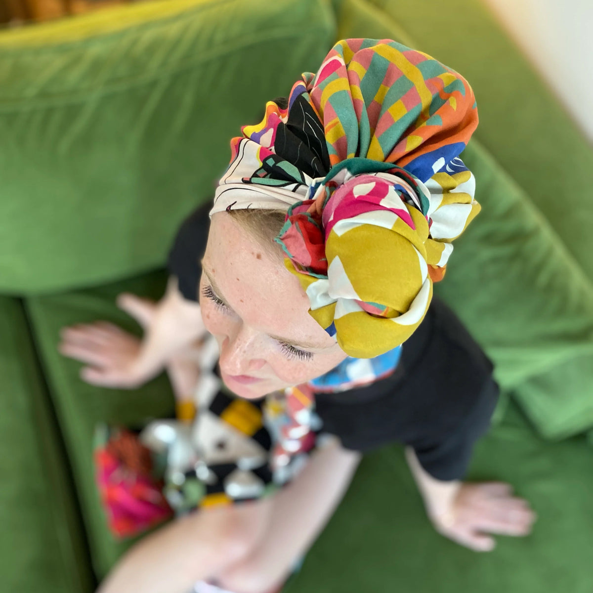 Child wearing a colorful headscarf on a green couch