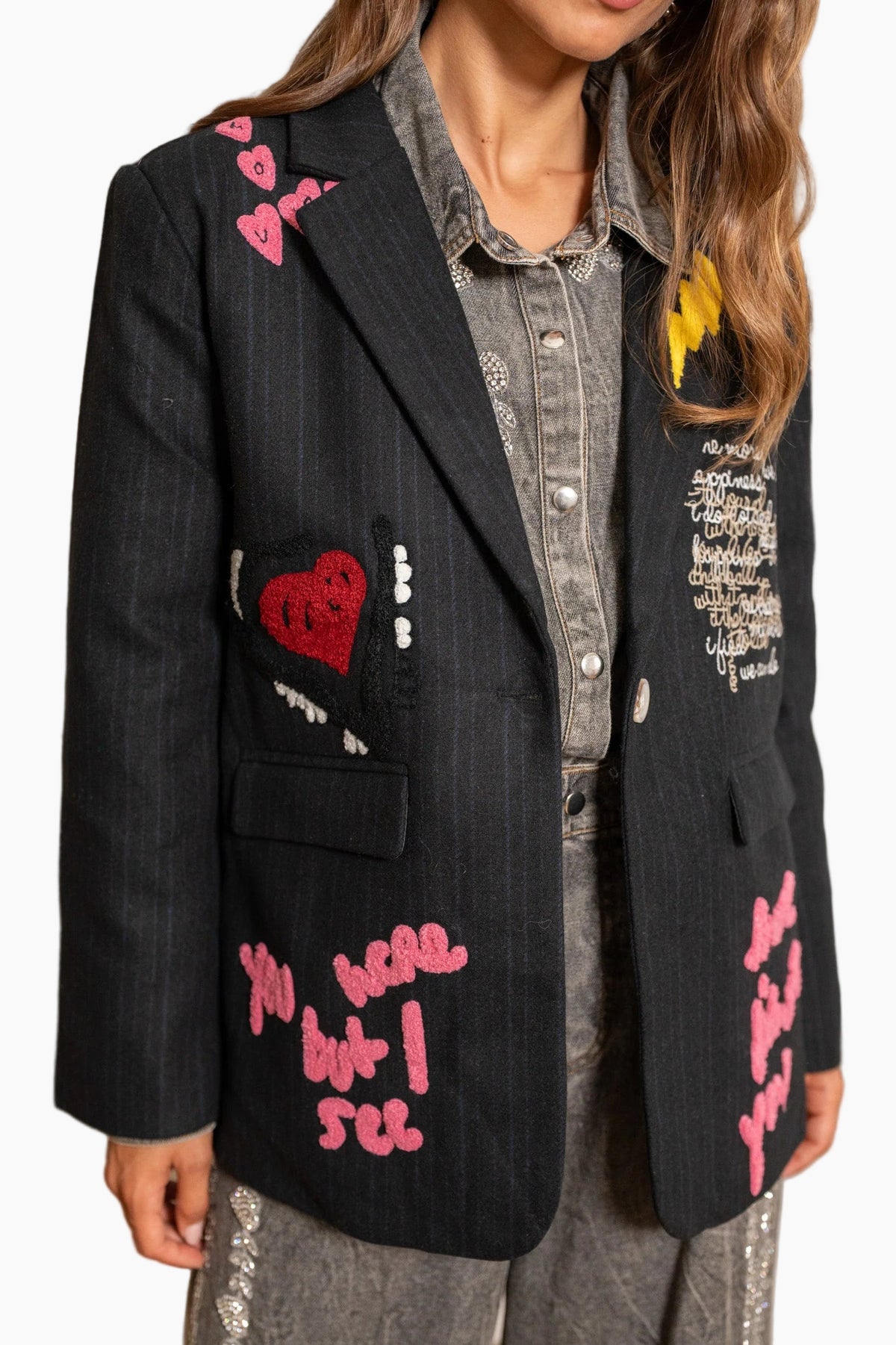 Person wearing a black blazer with colorful text and heart designs.