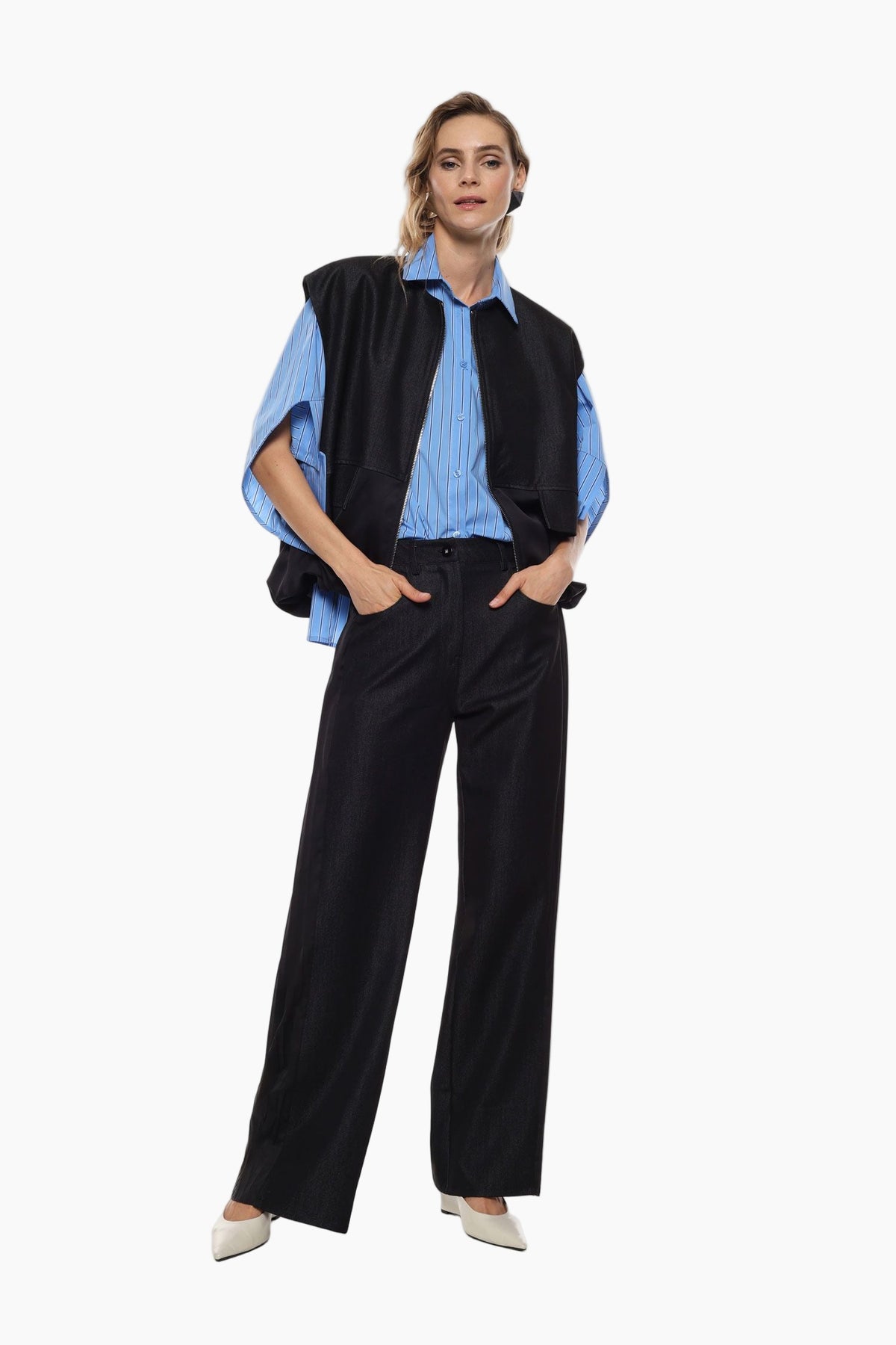 Woman wearing a black vest over a blue shirt with black pants 