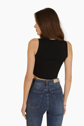 Woman wearing a black sleeveless top and blue jeans 