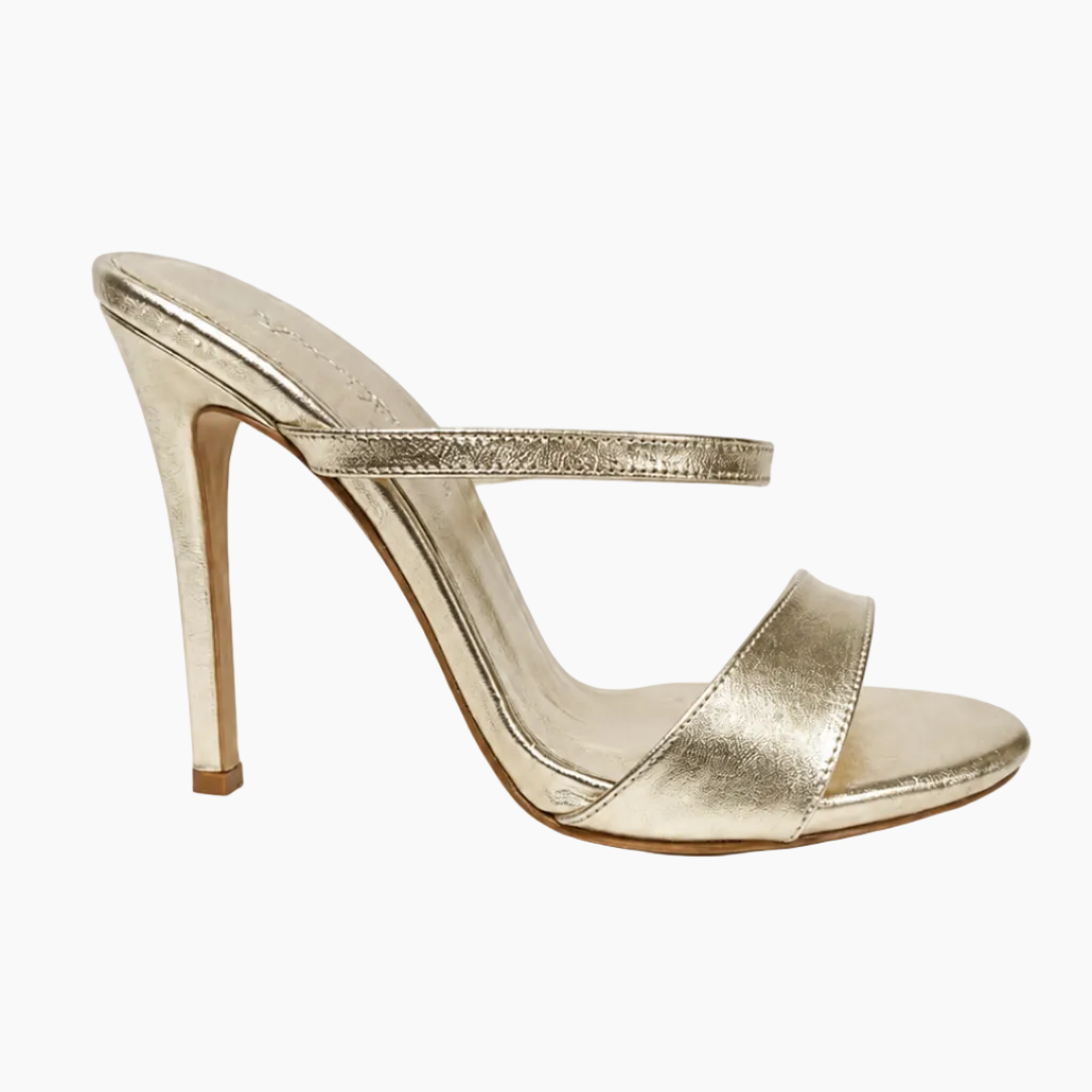 A metallic gold high-heeled sandal with an open toe, a slim stiletto heel, and a thin embellished ankle strap, shown from a side profile on a white background.