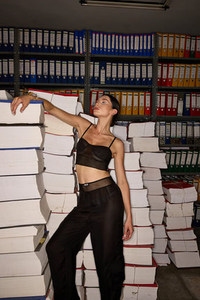 Woman in a black outfit standing among stacks of binders in an office setting