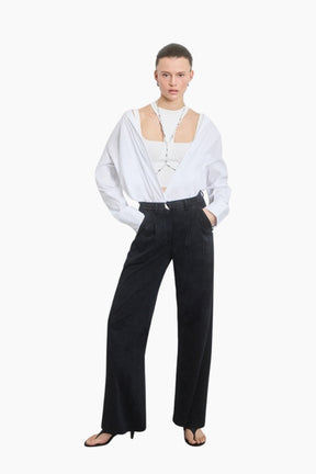 Person wearing a white blouse with cut-out design and black pants