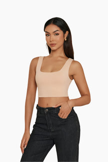 Woman wearing a beige crop top and black jeans