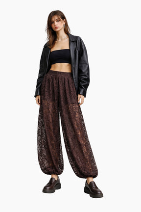 Woman wearing a black jacket, black top, and brown patterned pants on a white background