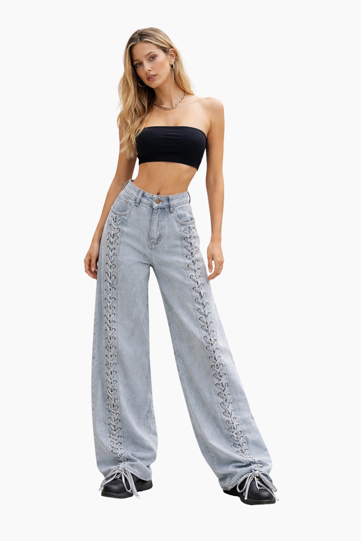 Woman wearing a black strapless top and light blue jeans with lace details on a white background