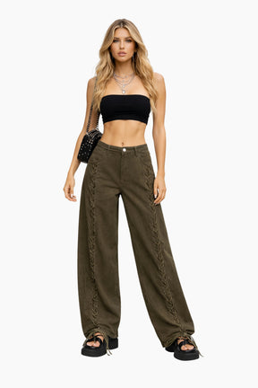Woman wearing a black crop top and olive green pants on a white background