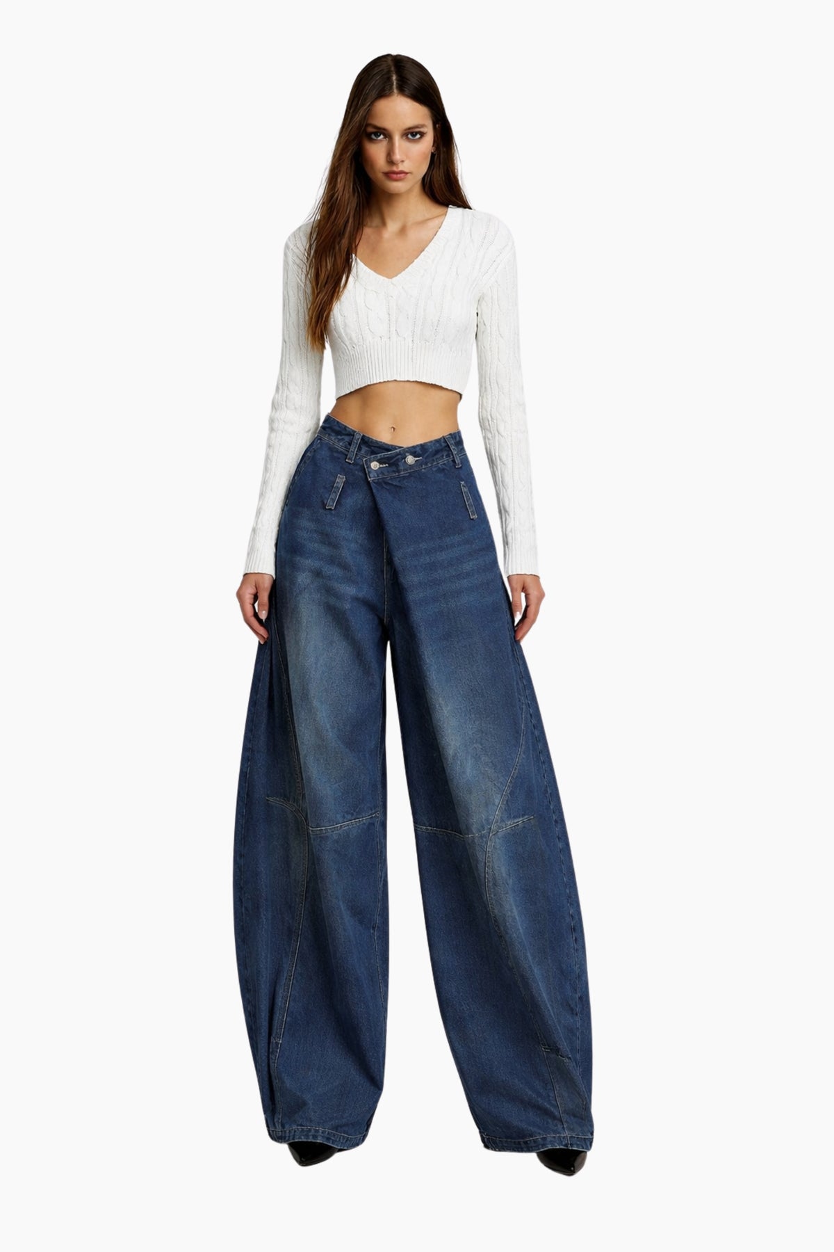 Woman wearing a white long-sleeve top and blue wide-leg jeans on a white background